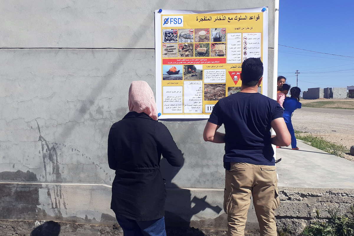 Villagers studying an EORE information poster in Iraq Villagers studying an EORE information poster in Iraq
